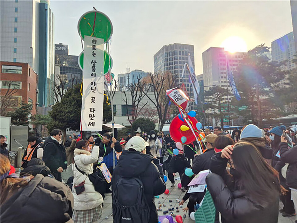 1월 18일 서울 종로 보신각, 공공운수노조 의료연대본부 주최 "내란성 급체 내리는 집회" 퍼포먼스로 박 터트리기 중인 모습. 터트려진 박 안에 "의료는 상품이 아닌 곳 다만세", "윤석열 퇴진" 현수막이 보인다.